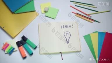 文字的想法和灯泡写在记事本与板标记和办公室配件灯泡想法的标志出现